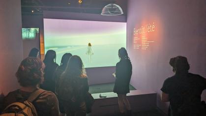 A curator demonstrates interactive features of MOMI's Auriea Harvey exhibition. Here, visitors are invited to explore one of Harvey's video games using a game console. 